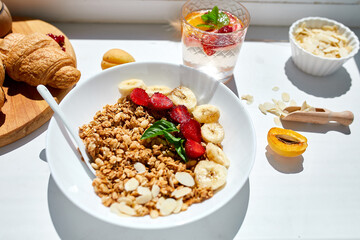 Healthy breakfast bowl, fresh granola, muesli berries strawberry, banana on white table in hard lights, Top view, Copy space. Clean eating, detox, dieting, vegetarian food concept