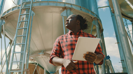 African farmer using laptop in front of the silo storage system. High quality photo © CameraCraft