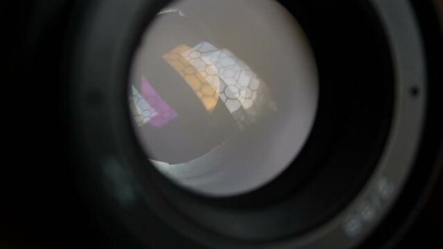 A movement of the aperture flaps on the camera lens. Aperture photo lens close-up. Multi-colored reflections of the window in the camera lens.