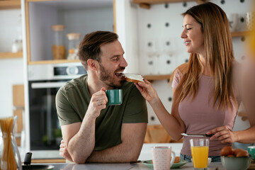 Young couple making breakfast at home. Loving couple eating sandwich in kitchen..