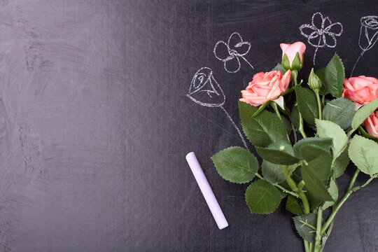 Bouquet of roses is front of the school board. Drawing on the school board with chulk.