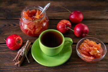 Apple jam with cinnamon and tea on a wooden table. Harvest preservation. Vegetarian food.