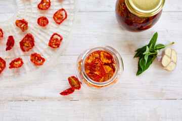 Homemade sun dried tomatoes with herbs, garlic in olive oil in a glass jar