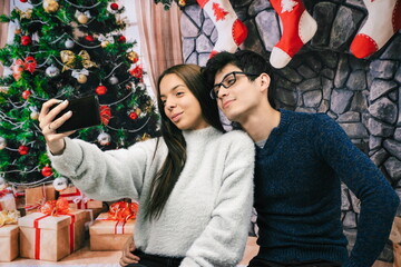 Couple taking a picture with mobile, Christmas background