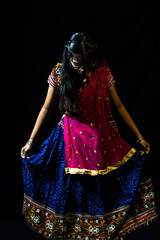 Indian girl in traditional chaniya choli for navratri with a fashionable hairstyle poses in studio...