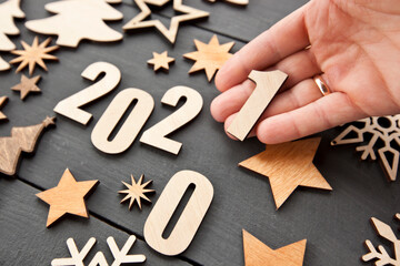 A lot of wooden christmas decorations and the woman's hand changes the year 