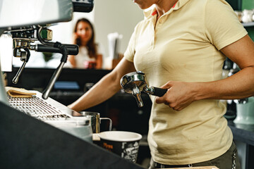 Woman coffee shop worker preparing coffee on professional coffee machine