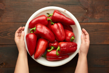 female hands holding a large white plastic bowl with red pepper