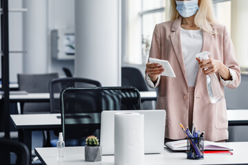Return to work, workplace hygiene and new normal. Blond woman in business suit in protective mask...