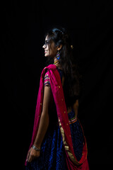 Indian girl in traditional chaniya choli for navratri with a fashionable hairstyle poses in studio...