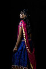 Indian girl in traditional chaniya choli for navratri with a fashionable hairstyle poses in studio...