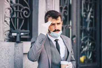 A young businessman goes to work during the morning, has gloves and a mask on his face, pauses to...