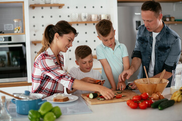 Mother and father making breakfast with sons. Young family preparing delicious food in kitchen..