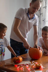 Fototapeta premium Dad and his sons make a pumpkin for halloween