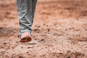 Horse whisperer walking barefoot on the sandpit. Moments before the show begins, natural feeling with the ground and the animal. Rodeo and ranch lifestyle, trainer, equestrian sports moment.