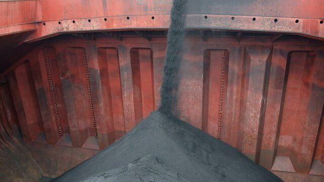 View of loading of iron ore concentrate in bulk into cargo hold of bulk carrier