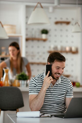 Young man working and talking to the phone. Handsome man working at home..