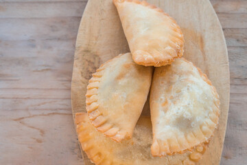 Empanadas on wood surface, perfect golden color and rustic and elegant presentation, seen from above.