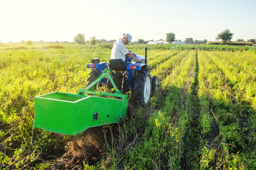 Obraz premium A farmer on a tractor drives across the field and digs potatoes. Farming and farmland. Harvesting potatoes in autumn. Countryside. Food production. Extract root vegetables to surface.