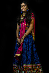 Indian girl in traditional chaniya choli for navratri with a fashionable hairstyle poses in studio...