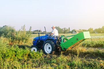 Obraz premium A farmer on a tractor drives across the farm field. Potato harvest campaign. Farming, agriculture. Countryside farmland. The use of mechanical engineering in agriculture. Harvesting potatoes in autumn