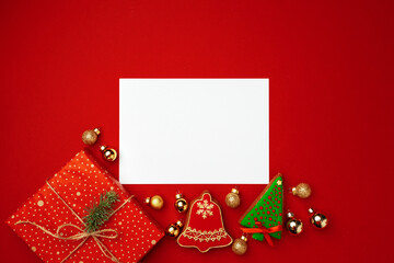 Blank sheet of paper with Christmas gift and gingerbread cookies on red background