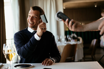 Businessman paying the bill with a credit card in restaurant.