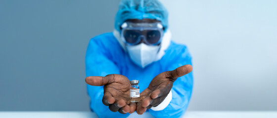 Close up on Vaccine. African American scientist in laboratory holding vial of coronavirus vaccine....