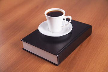 Book and coffee are isolated on a wooden background.