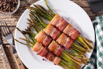 Green asparagus wrapped with bacon on wooden table. Top view	