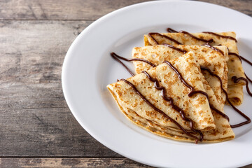 Sweet crepes with chocolate on wooden table. 	