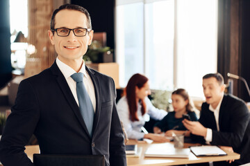 A man in a tie stands in the office and smiles.