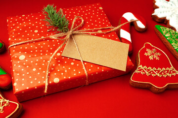 Blank sheet of paper with Christmas gift and gingerbread cookies on red background