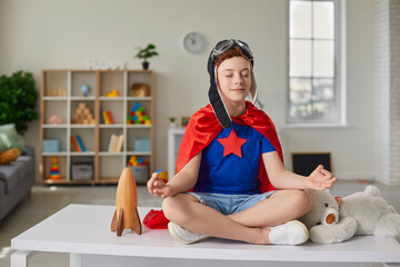Funny little boy sitting on the table in the lotus position in the nursery.