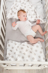 top view of infant boy in baby romper lying in crib