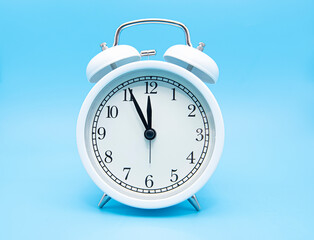 White classic alarm clock on blue background, concept picture