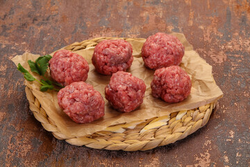 Raw meatball over wooden background