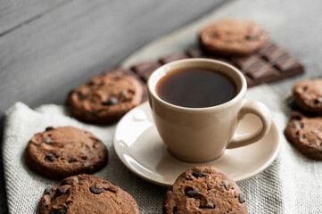 Coffee cup with cookies and chocolate on wooden table background. Mug of black coffee with chocolate cookies. Fresh coffee beans.