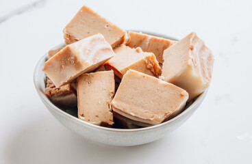 Raw vegan peanut butter fudge on a white marble background.