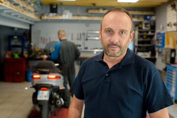 man in the motorbike mechanic shop posing