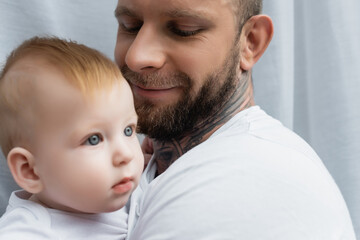 selective focus of joyful bearded man holding infant son in hands