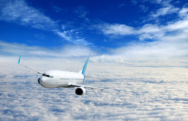 Fototapeta na wymiar White airplane flying above clouds in the sky
