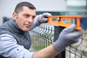 a worker checks the level of metal fence