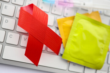 Two condoms and red ribbon on keyboard. 1st december anti-aids day concept