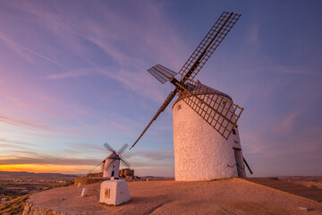Beautiful white spanish windmill on the hill at fairy blue pink gold sunset near the castle in...