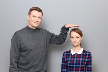 Tall man is showing height of short woman, people of different heights