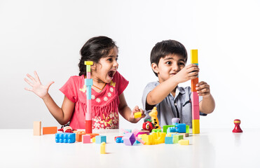 Indian cute kids playing with colourful plastic toys or blocks against white background