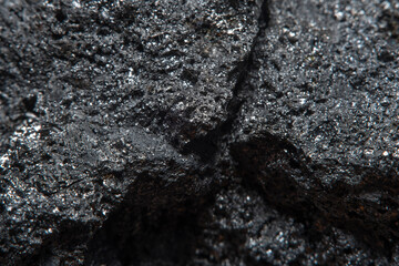 Blurred black background in soft focus with hard coal at high magnification. An image on the theme of geology and the extraction of minerals and natural fuels.