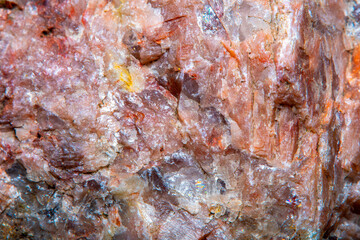 Background with the surface of a piece of red granite interspersed with quartz in soft focus under high magnification