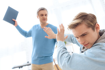 Obraz premium Father swings to hit his son with book.